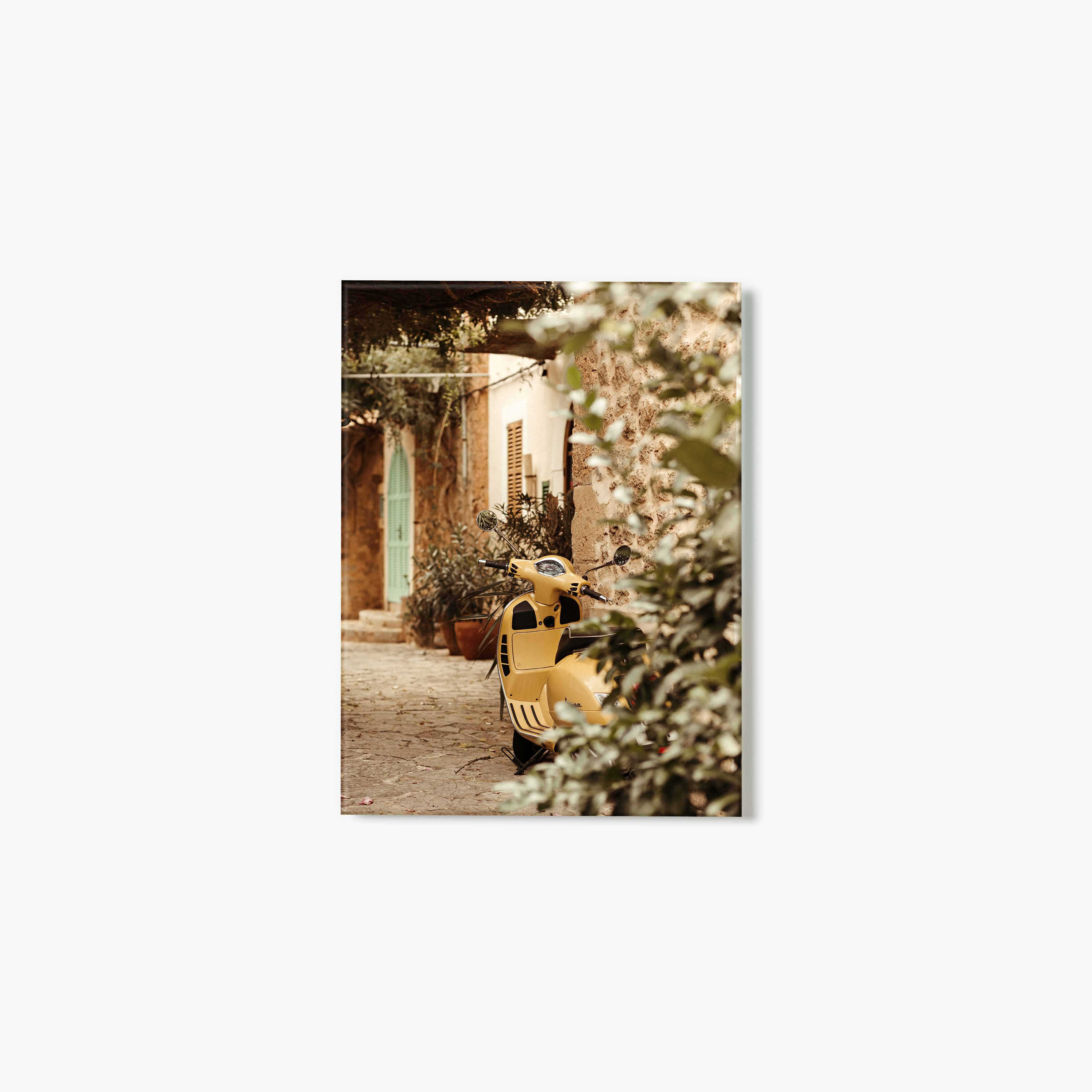 Yellow scooter parked in a quaint outdoor setting with a building and greenery.